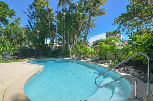 a swimming pool in a yard with palm trees at Seascape Holidays - Tropical Reef Apartments in Port Douglas