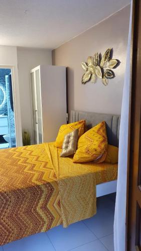 a bedroom with a bed with yellow sheets and pillows at Studio havre aux hibiscus avec piscine proche de la mer in Sainte-Anne