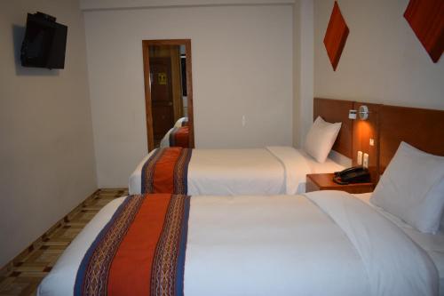 a hotel room with two beds and a television at Mantu Boutique in Machu Picchu