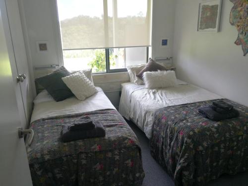 two beds in a room with a window at Kaka Lodge at Kotare House in Tawharanui