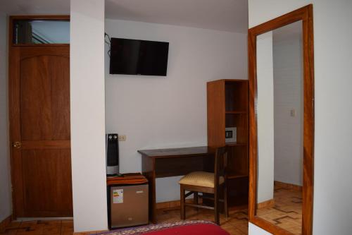 a room with a desk and a tv on a wall at Mantu Boutique in Machu Picchu