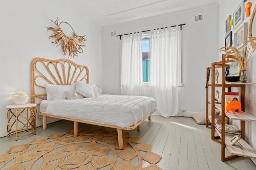 a white room with a bed and a chair at Bondi Surf Cottage in Sydney