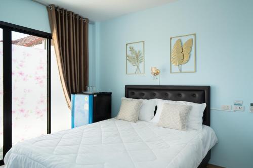 a bedroom with a large bed with blue walls at Brown Home Sattahip @ 19 in Sattahip
