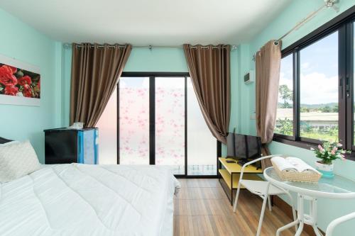 a bedroom with a white bed and a table and chairs at Brown Home Sattahip @ 19 in Sattahip