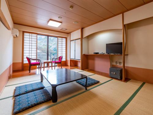 a living room with a table and chairs and a television at Shiobara Onsen Yashio Lodge in Nasushiobara