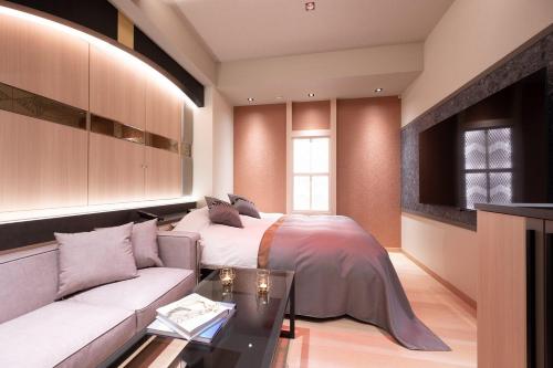 a bedroom with a bed and a couch at HOTEL K-NEXT Adult Only in Saitama