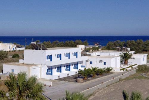 a large white building with blue windows and the ocean at Mary Rooms in Perivolos