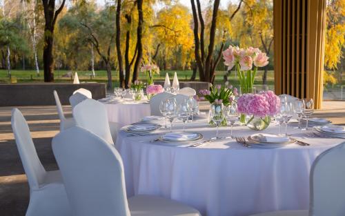 a table with white tables and chairs and flowers at Swissôtel Wellness Resort Alatau Almaty in Almaty