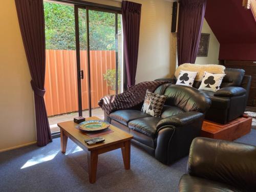 a living room with a leather couch and a coffee table at Harbour Lodge in  Lyttelton