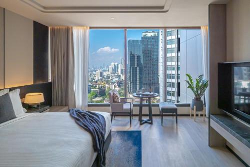 a hotel room with a bed and a view of a city at Ascott Thonglor Bangkok - SHA Plus Certified in Bangkok