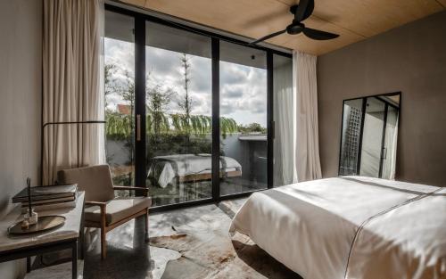 een slaapkamer met een bed en een groot glazen raam bij OXO Townhouses Berawa Canggu in Canggu