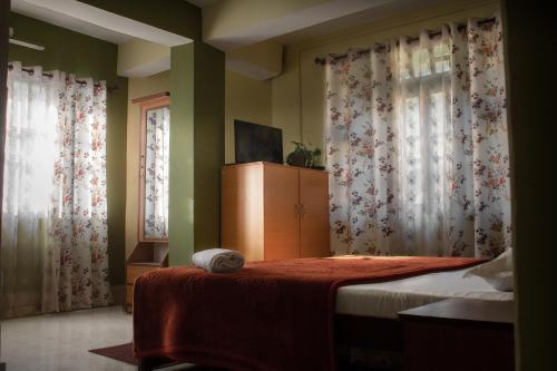 a bedroom with a bed and two windows with curtains at Ashraya Boutique Homestay in Rongli