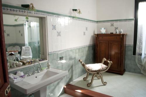 Łazienka z umywalką i krzesłem obok lustra w obiekcie B&B Corte Leopoli w mieście Buscoldo