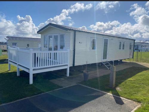 a small white house with a porch on a field at Sandy bay mariners rise in North Seaton