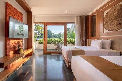Harsono Boutique Resort Bali في غيانيار: سريرين في غرفة الفندق مع موقد