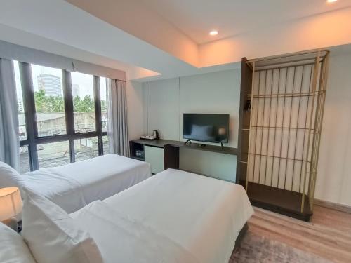 a hotel room with two beds and a flat screen tv at VIVA LA VIDA HOTEL in Bangkok