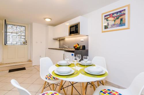 a dining room with a white table and white chairs at Apartment Domix in Dubrovnik