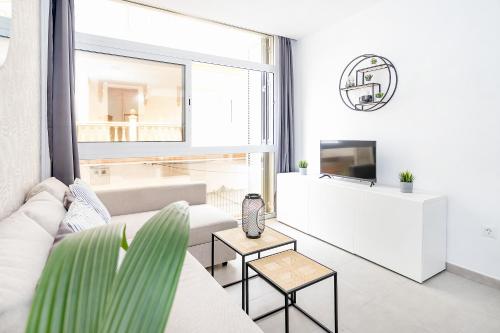a white living room with a couch and a tv at Cala de Mijas Summer Vibes in Mijas Costa
