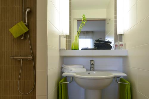 a bathroom with a sink and a mirror at Brit Hotel Reims Croix Blandin in Reims