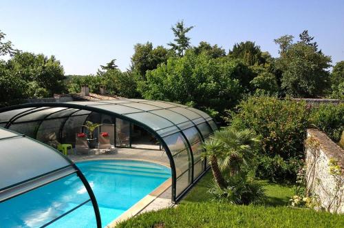 une serre en verre à côté d'une piscine dans l'établissement Le Puits Sainte Claire, à Courçon