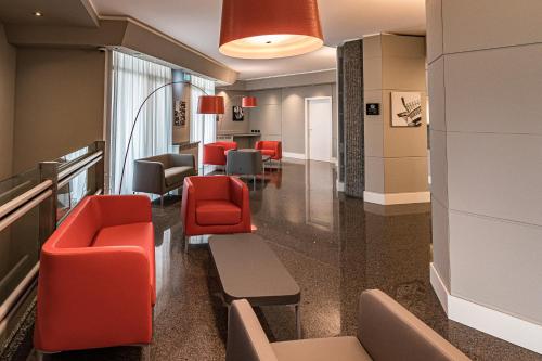 a waiting room in a hospital with red chairs at BB Hotels Smarthotel Re Milano Nord in Sesto San Giovanni
