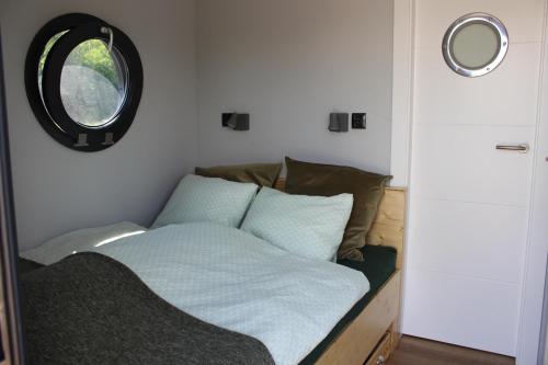 a bed in a room with a round window at Hausboot Schwanennest in Kirchberg an der Raab