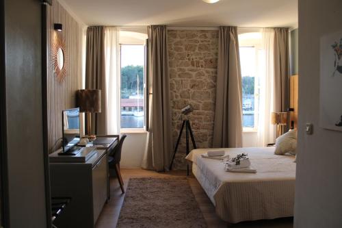 a hotel room with a bed and a desk and windows at Olife Guesthouse in Milna