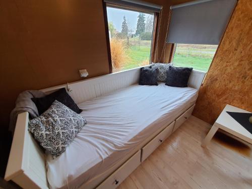 Bett in einem Zimmer mit einem großen Fenster in der Unterkunft Mobilheim v LVA 1 in Podivín