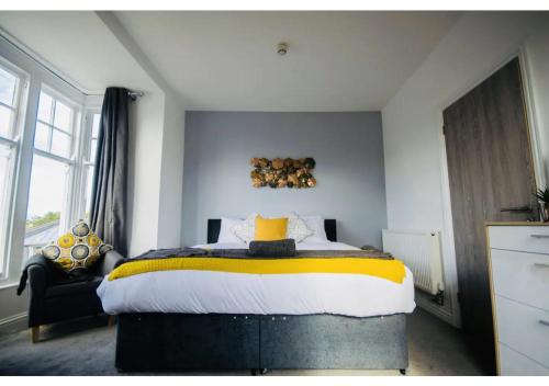 a bedroom with a large bed with yellow and white sheets at ALTIDO House in Camborne, Cornwall in Camborne