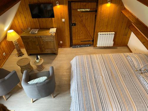 a room with a bed and two chairs and a television at L'atypique au pays de Honfleur in Genneville