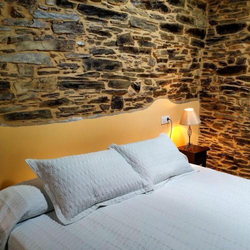 a bedroom with a bed with a stone wall at Casa Carballeira in Villarfernando