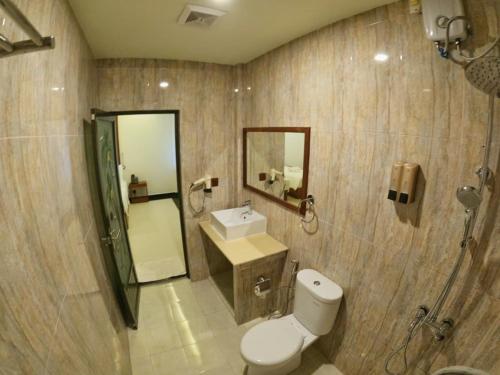 W łazience znajduje się toaleta, umywalka i lustro. w obiekcie Beach Stone w mieście Gulhi