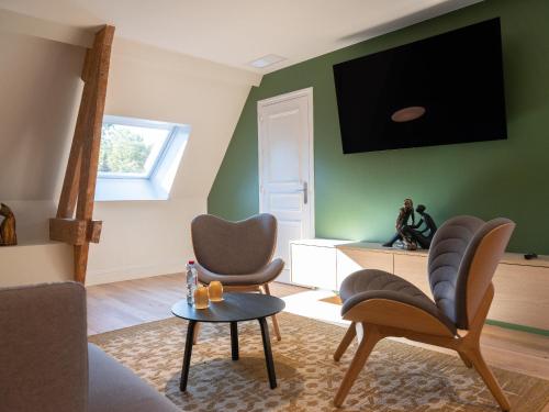 sala de estar con 2 sillas y TV en la pared en Le Château De Beaulieu, en Busnes