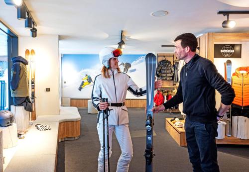 a man and a woman holding skis in a store at Hôtel VoulezVous by Les Etincelles in Tignes