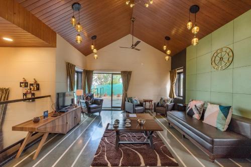 a living room with a couch and a table at SaffronStays Casa Tranquil, Panchgani - pet-friendly veg only pool villa in Panchgani