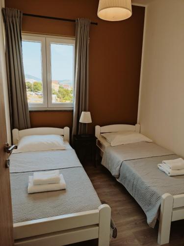 two beds in a room with a window at Apartmani Luka in Grebaštica