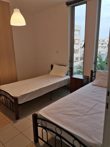 two beds in a room with a window at City Flats 308 in Larnaca