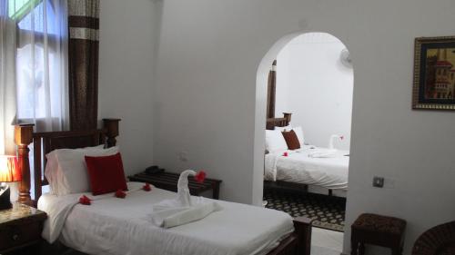 a hotel room with two beds and a mirror at Al-Minar Hotel in Zanzibar City