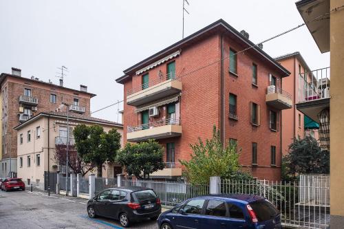 dwa samochody zaparkowane przed ceglanym budynkiem w obiekcie Appartamento Bernini in zona Sant'Orsola w Bolonii