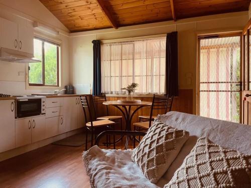 a living room with a kitchen and a table with chairs at Willuna Sanctuary in Chiltern