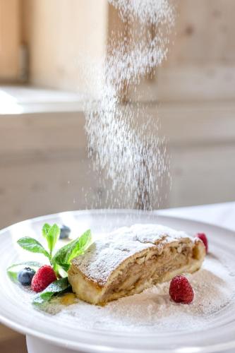 a plate with a piece of food with powdered sugar on it at Hotel Schmuckhof in Chiusa