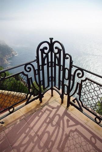 a black iron fence with a view of the ocean at El Far Hotel Restaurant in Llafranc