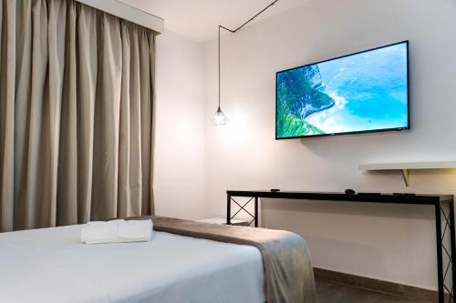 1 dormitorio con 1 cama y TV de pantalla plana en la pared en Front Comfort Teófilo Otoni, en Teófilo Otoni