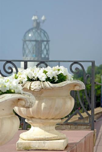 a stone vase filled with white flowers next to a fence at El Far Hotel Restaurant in Llafranc