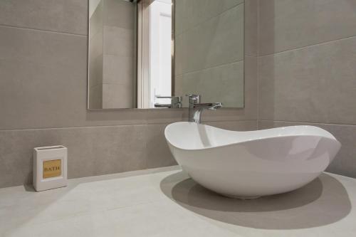 a white bath tub in a bathroom with a mirror at Irini Rooms in Naousa