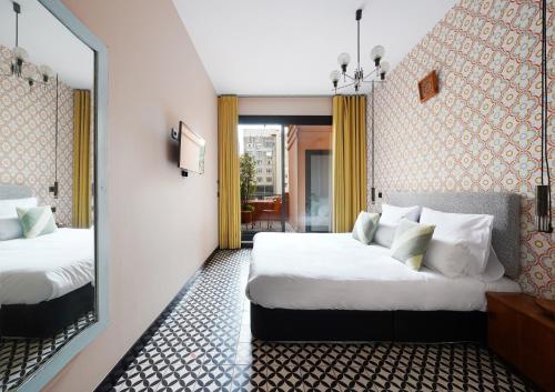 a hotel room with two beds and a mirror at numa l Roca Rooms & Apartments in Barcelona