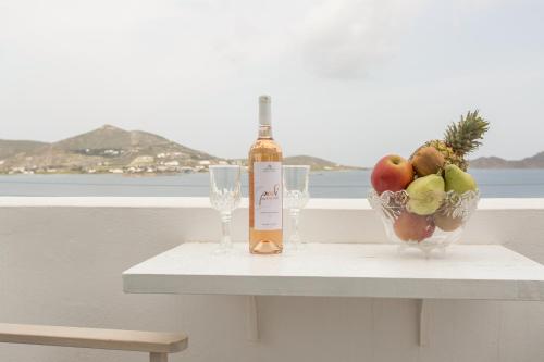 a bottle of wine and a bowl of fruit on a table at Irini Rooms in Naousa