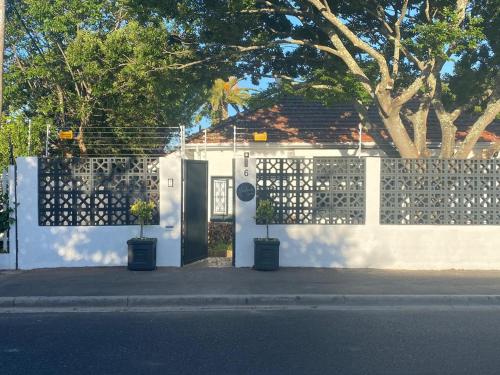 a white house with a door and a fence at Thelma & You in Cape Town