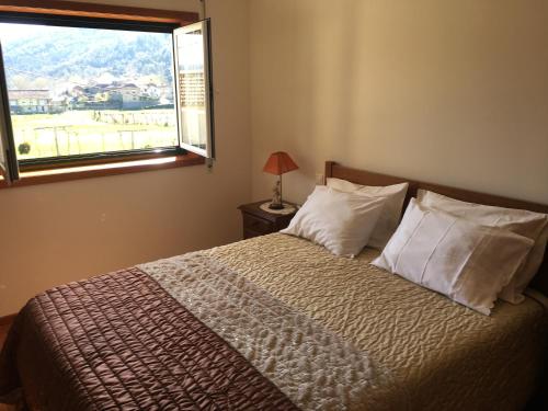 a bedroom with a large bed with a window at Casa do Reguengo in Arouca