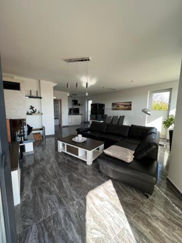 ein Wohnzimmer mit einem schwarzen Sofa und einem Tisch in der Unterkunft Haus Hannah in Ostseebad Sellin